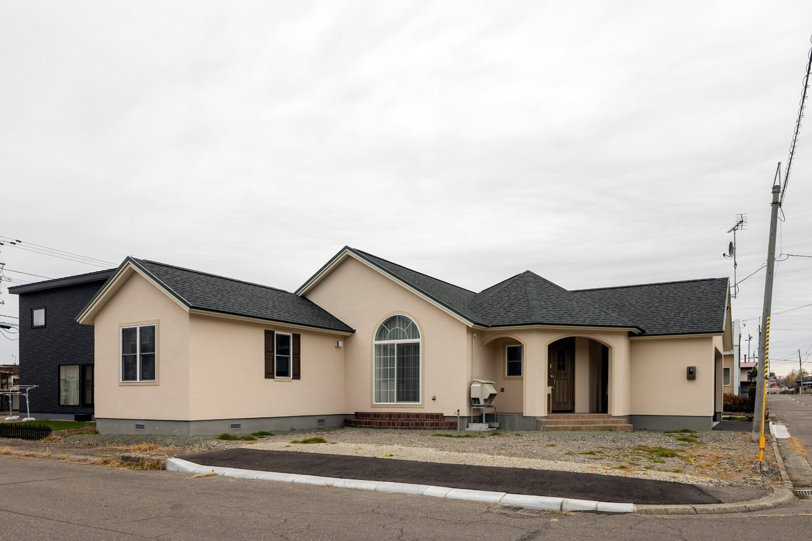 角地の敷地形状を生かしたL型のフォルムに、三角屋根と寄棟屋根を組み合わせ、塗り壁で仕上げた外観。個性的な佇まいが、地域でも話題に
