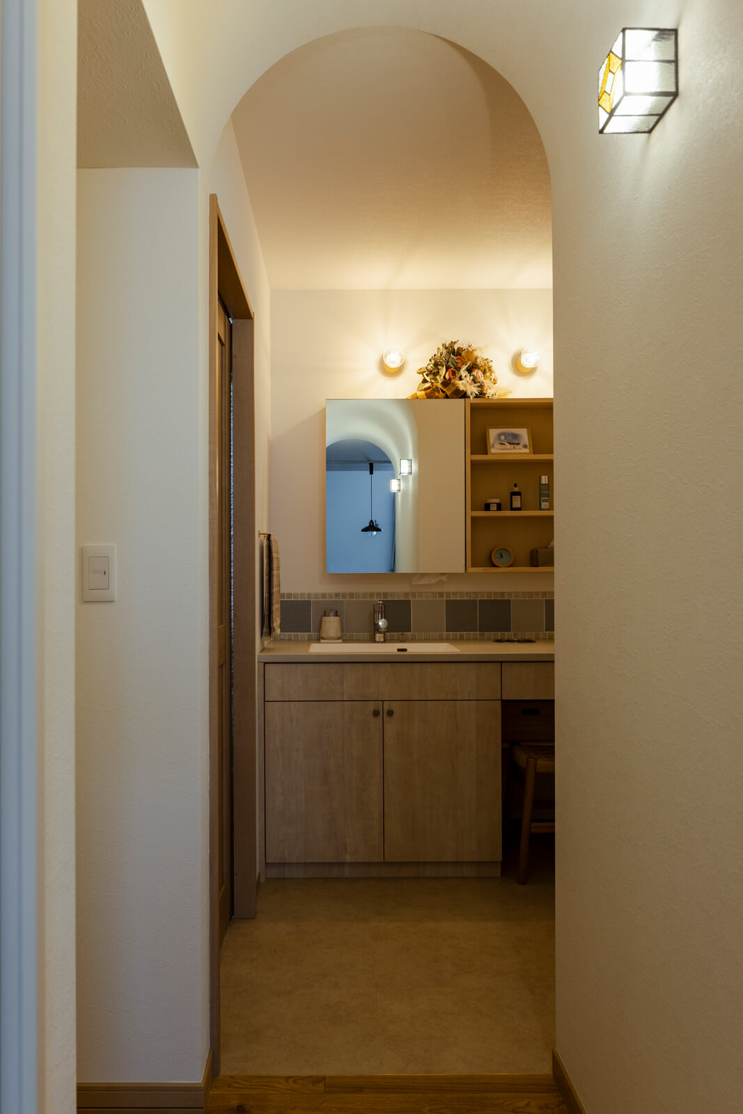 ダイニングから洗面台を望む。手前にあるアール型の開口が、空間にエレガントさを感じさせる