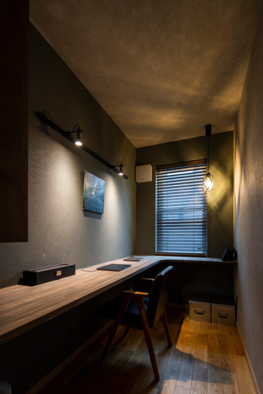 ダイニングの一角にある壁クロスを張ったハイドアを開けると、ダークな色調でまとめたOさんの書斎スペースが出現。こもり感のある空間は、まさに大人の隠れ家