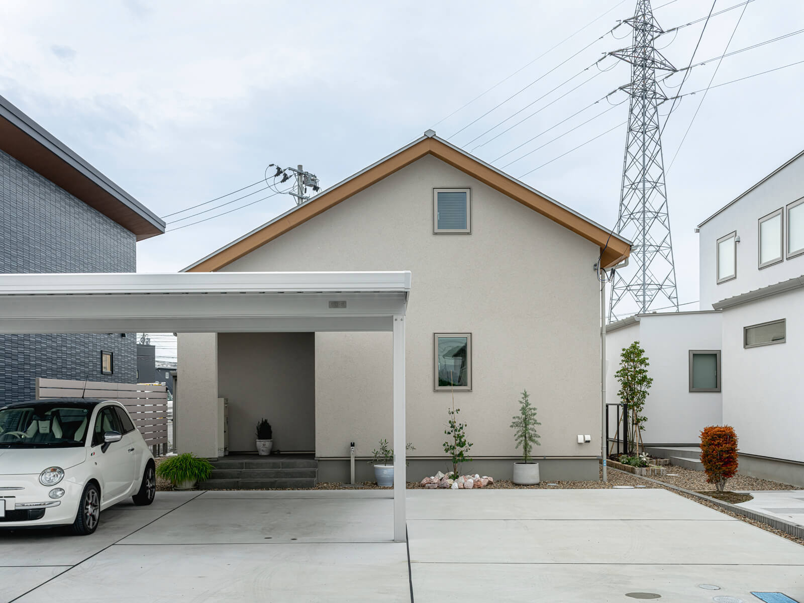 切妻屋根と木仕上げの軒天が印象的なKさん宅のファサード。正面は塗り壁、側面や背面はサイディングと、人目につく壁とつかない壁で外壁材を使い分け、コストとデザインのバランスを図っている