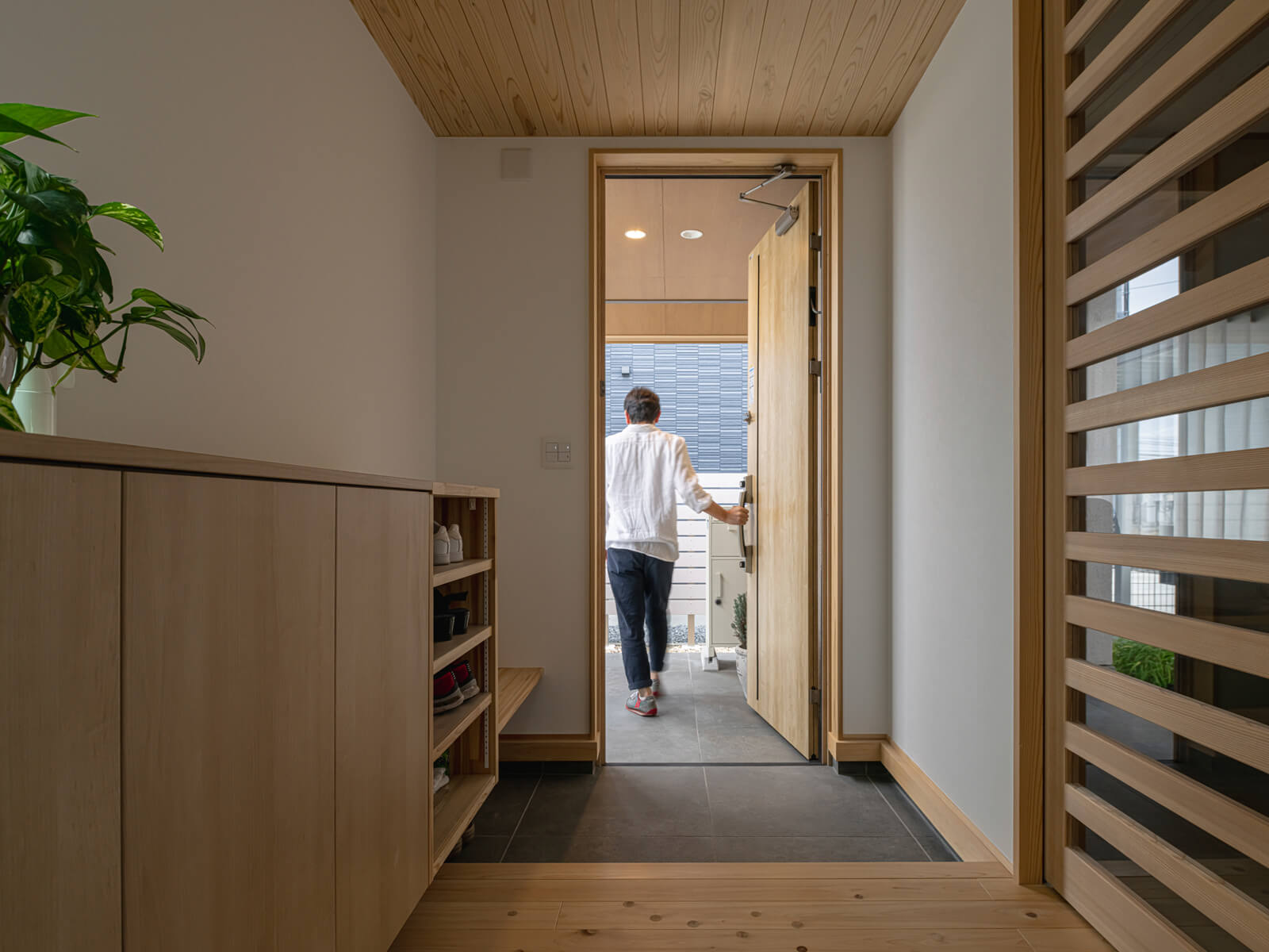 ヒノキの無垢床、スギ板張りの天井に挟まれた木の温もりがあふれる玄関。シューズボックスや靴履き用ベンチなどの造作も空間になじんでいる