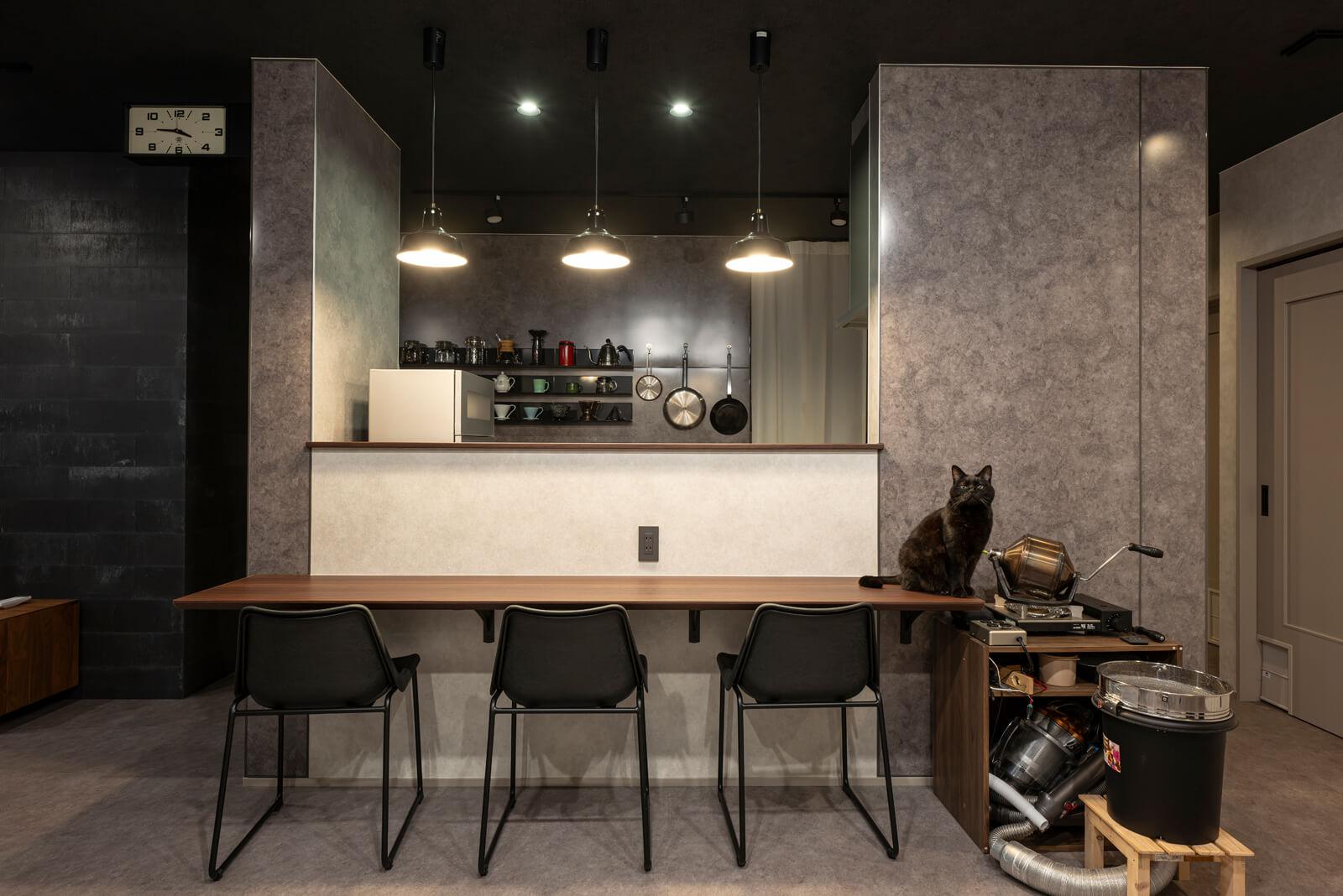 3連のペンダントライトがカフェ風のキッチンカウンター。外付けの食洗機を設置できるよう専用の水道を設けたため、キッチンと対面カウンターの間にある腰壁は通常より高めになっている。右下にあるのはTさんが自作したコーヒーを自家焙煎する装置