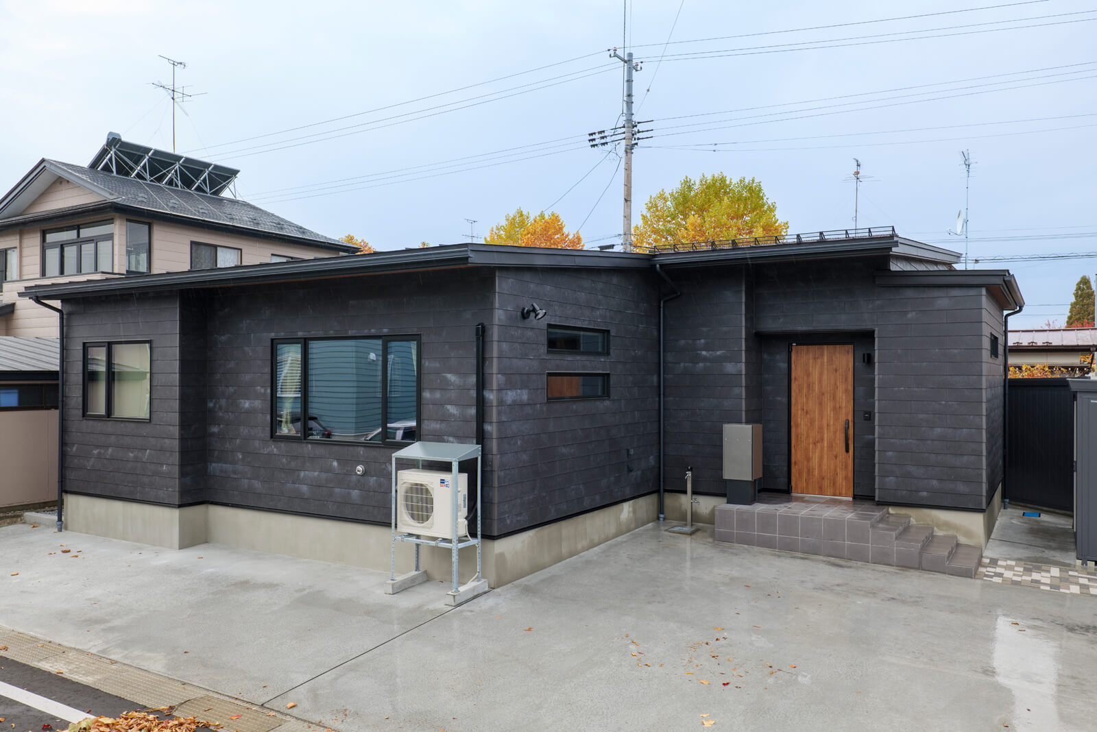 セメント製の外壁材を鎧張りした外観。一枚一枚の表情が絶妙に異なる。物置を設置して、室内の収納面積を小さくし、その分のスペースを居室として無駄なく使えるようにした