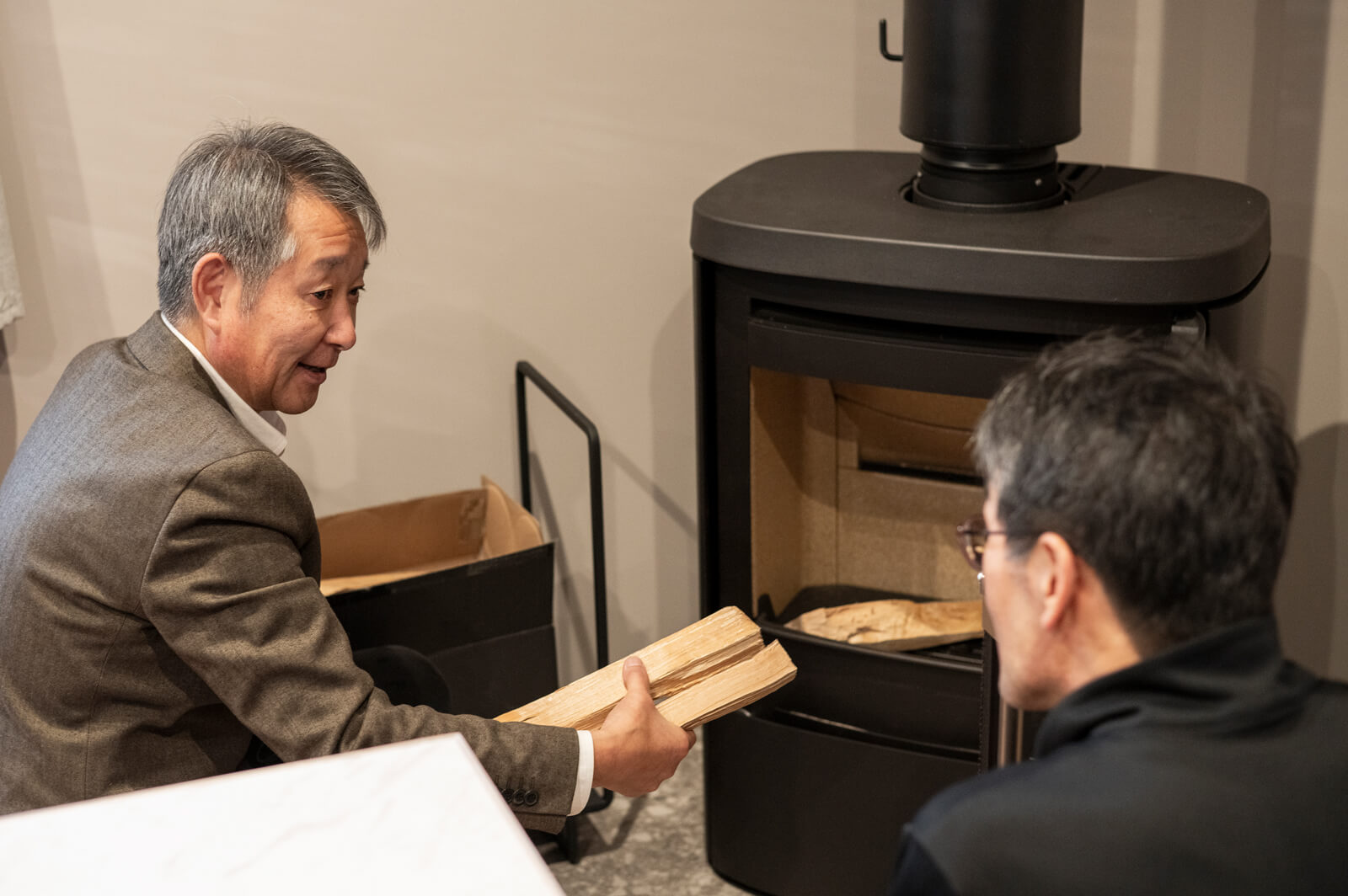 火入れ式用に持参した細めの薪を手に、Aさんに薪の置き方などを説明するコロポックルの橋口さん