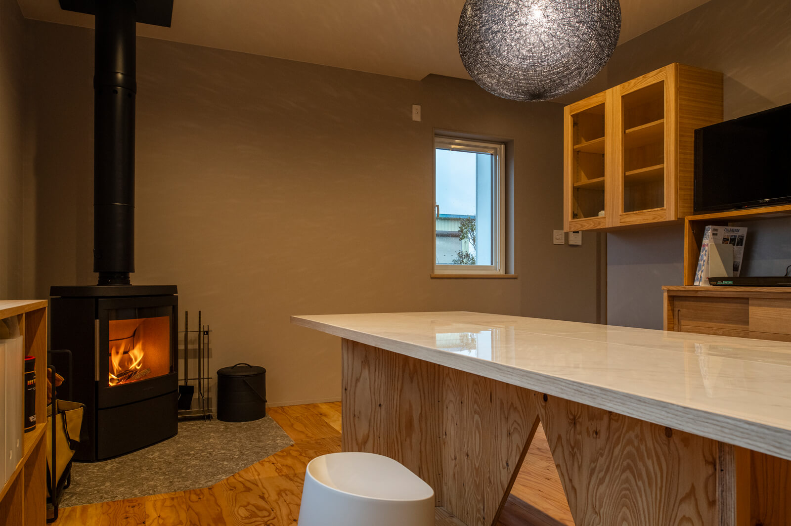 シンプルなインテリアでコーディネートされたダイニング・キッチンに、薪ストーブの炎が彩りを添える