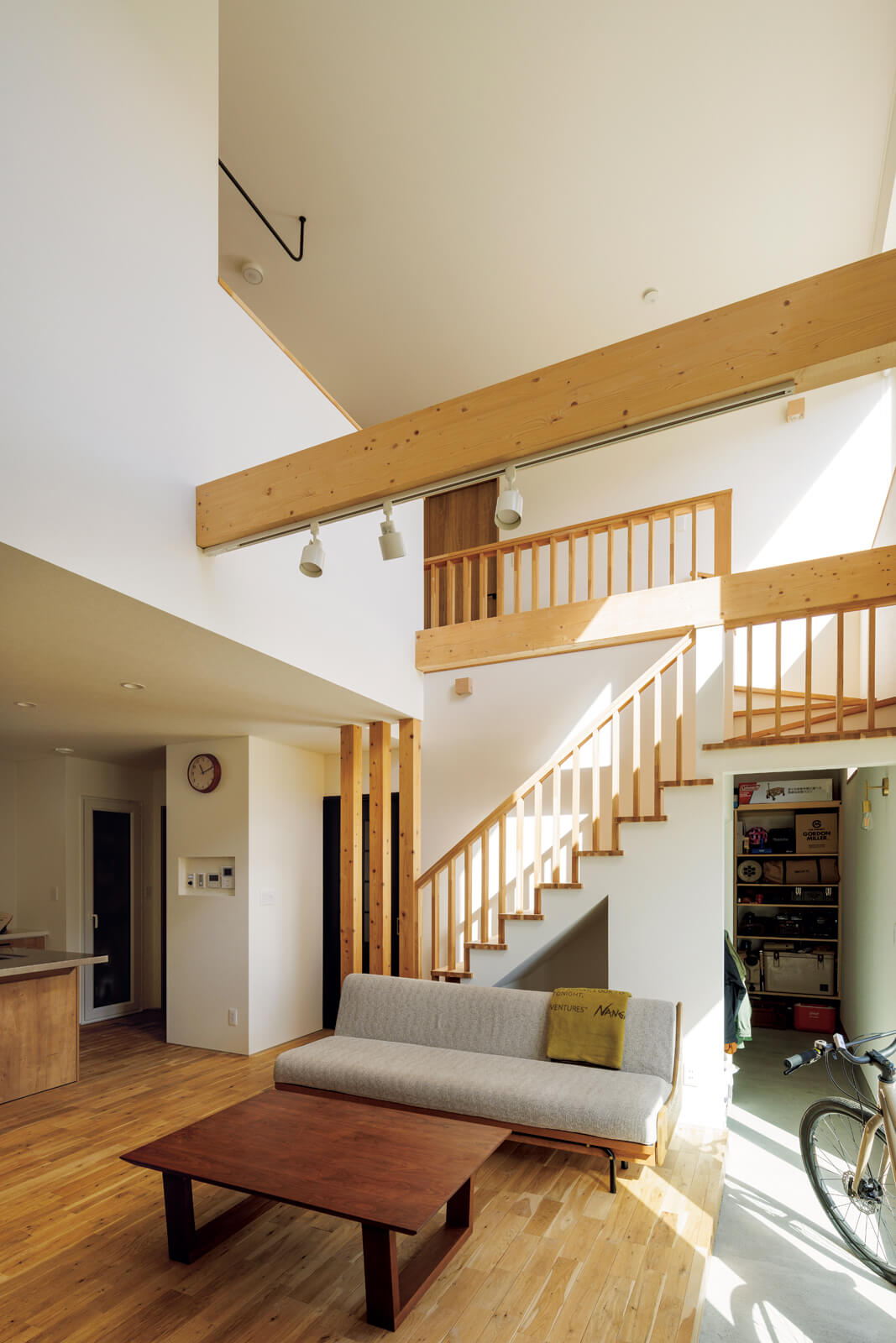 2階まで延びる吹き抜けと現しの梁、リビング階段、ナラの無垢床が心地よいハーモニーを奏でるリビングはご夫妻のお気に入り。Mさんの要望で施工中に階段踊り場の腰壁を手すりに変更したことで、開放感がさらにアップした