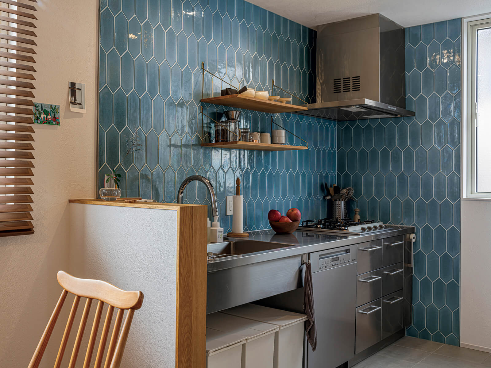 ブルーグレーのタイル仕上げのアクセントウォールが美しいOさん宅のキッチン空間。ステンレス製のキッチンはオーダーメイドで使い勝手が良く、料理がはかどる