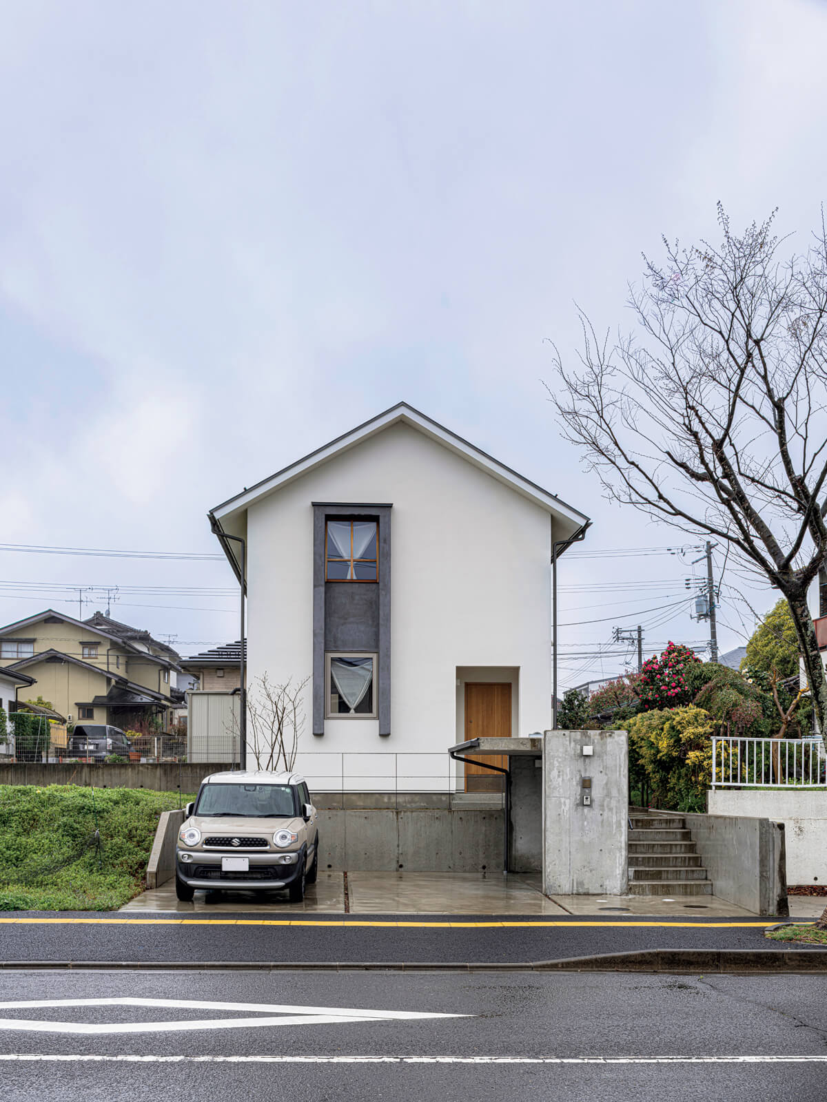 通り沿いにあって目を引く、三角屋根に白壁のシンプルなファサード。1階と2階で呼応する木とモールテックスの窓枠が個性を放つ