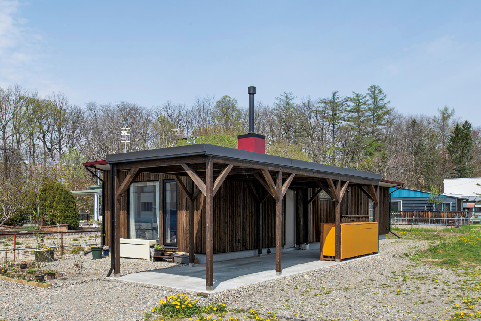 防風林を背景に佇む、赤い煙突囲いが目を引くTさん宅。「東京時代から庭づくりが好きでした。憧れていたのはリンゴの木を育てること。余市町でリンゴの木の苗木を購入しました」と奥さん