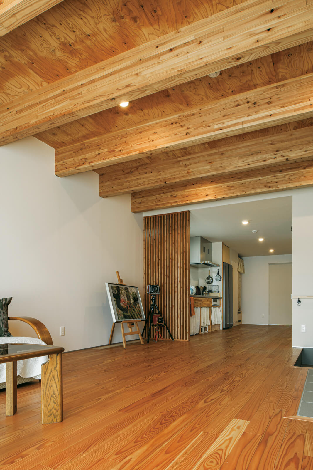 メイン空間となるリビング・ダイニングの天井は合板仕上げとし、現しの梁も含めて木の質感が伝わる心地の良い空間に。白い天井との素材の変化が、仕切りのない空間の緩やかなゾーニングにも一役買っている