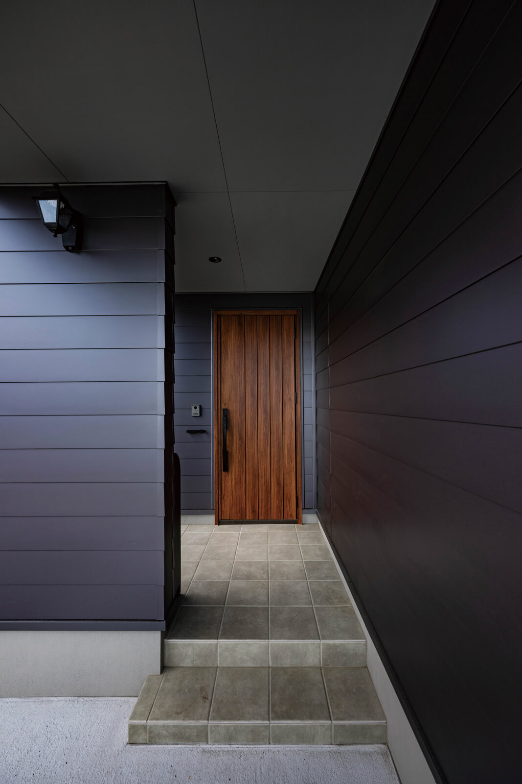 玄関ポーチは全体に屋根がかかっているので、雨や雪の日でも鍵を開けるまでの間に濡れる心配がない。地面と同じ高さになっている手前のスペースは自転車置き場で、ここにも屋根がかかっている