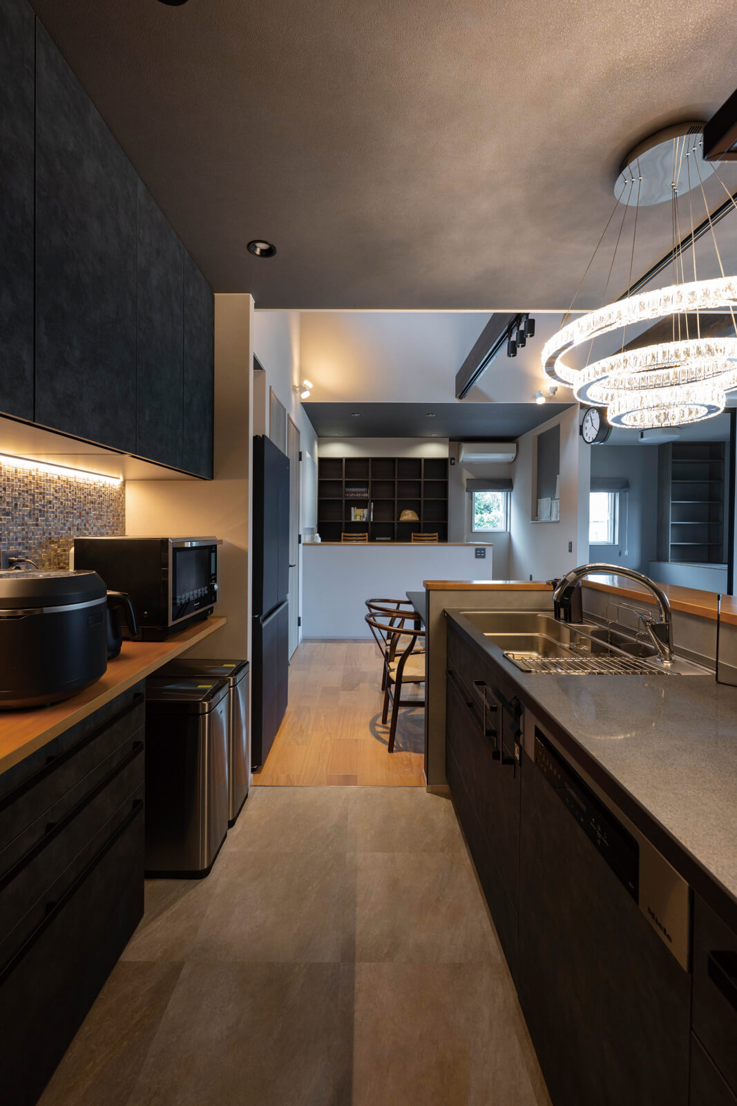 キッチンと背面収納の間は約1ｍ。大人が余裕を持ってすれ違える広さでありながら、一歩踏み出せばあらゆる道具に手が届く絶妙な距離。家電はあらかじめ置くものを決め、寸法に合わせて収納を設計した