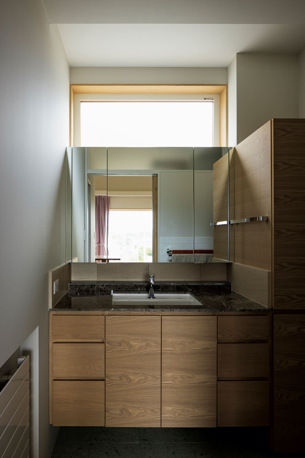 造作洗面台は、タオル類などをしまう収納も充実させた。床と洗面天板は天然石仕上げ