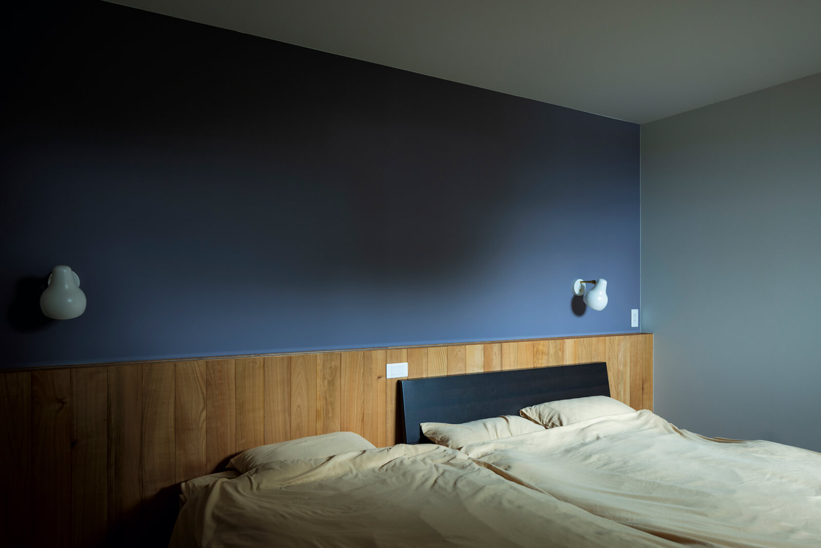 リビング階段奥には、アクセントウォールを用いたシンプルな寝室をレイアウト。夫婦の暮らしは1階のみで完結できる