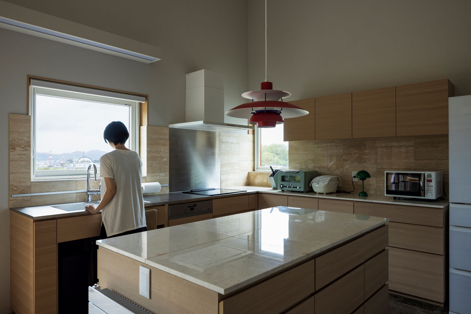 大きな窓を設えたL字型壁付けキッチンは造作仕様。アイランドカウンターも備え、作業もしやすく収納も十分。奥さんの希望で掃除がしやすいIHクッキングヒーターを採用した