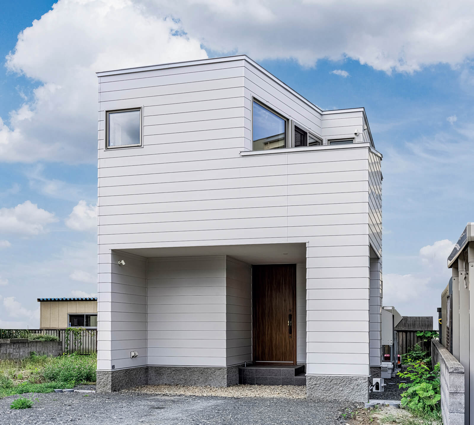 白い金属系サイディングを採用したすっきりとした外観。2階のリビングから山並みがより良く見えるよう建物の形状を調整した。また、外から中の様子をうかがうことができないよう、バルコニーの腰壁の高さにも配慮した