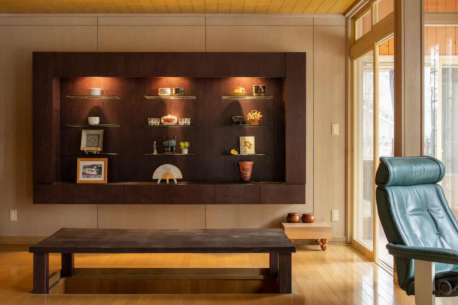 リビングには一枚板の座卓に掘りごたつ、間接照明を仕込んだ飾り棚を造作。右手奥へ進むと寝室がある