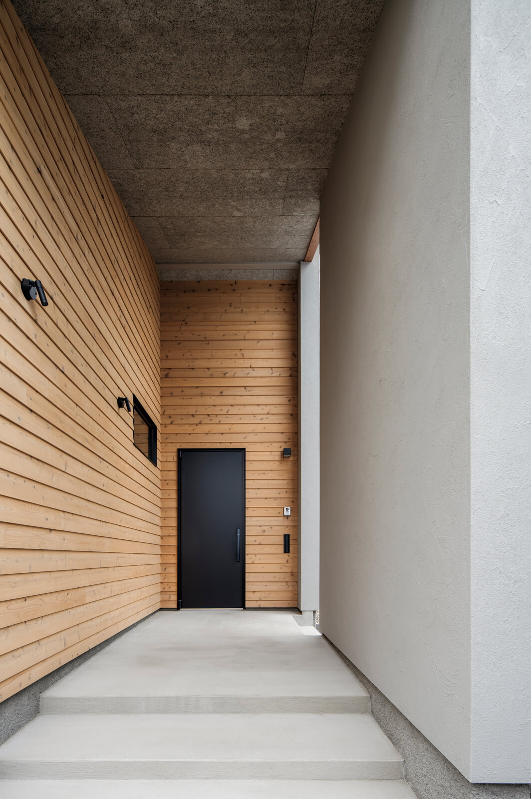 勾配屋根の高さが際立つアプローチ。道路と並行に伸ばすことで奥行きが生まれ、建物内部へと自然と意識が向く