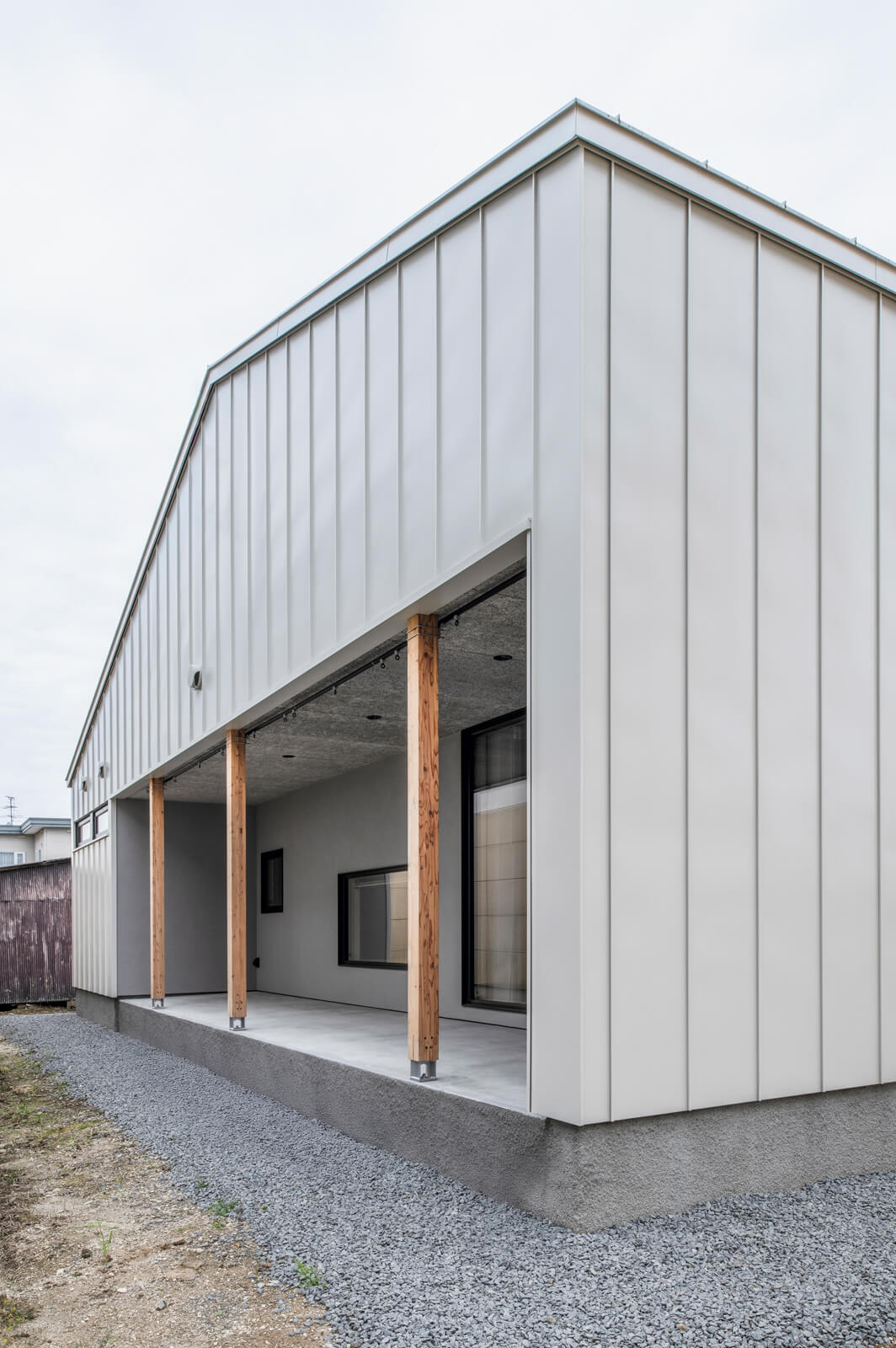 正面以外の外壁にはライトグレーのガルバリウム鋼板を採用。裏にはリビングとつながる広いモルタルのデッキがある。「柵を設けるなどして外構を整えたら、子どもの遊び場として活用したいと思っています」と奥さん