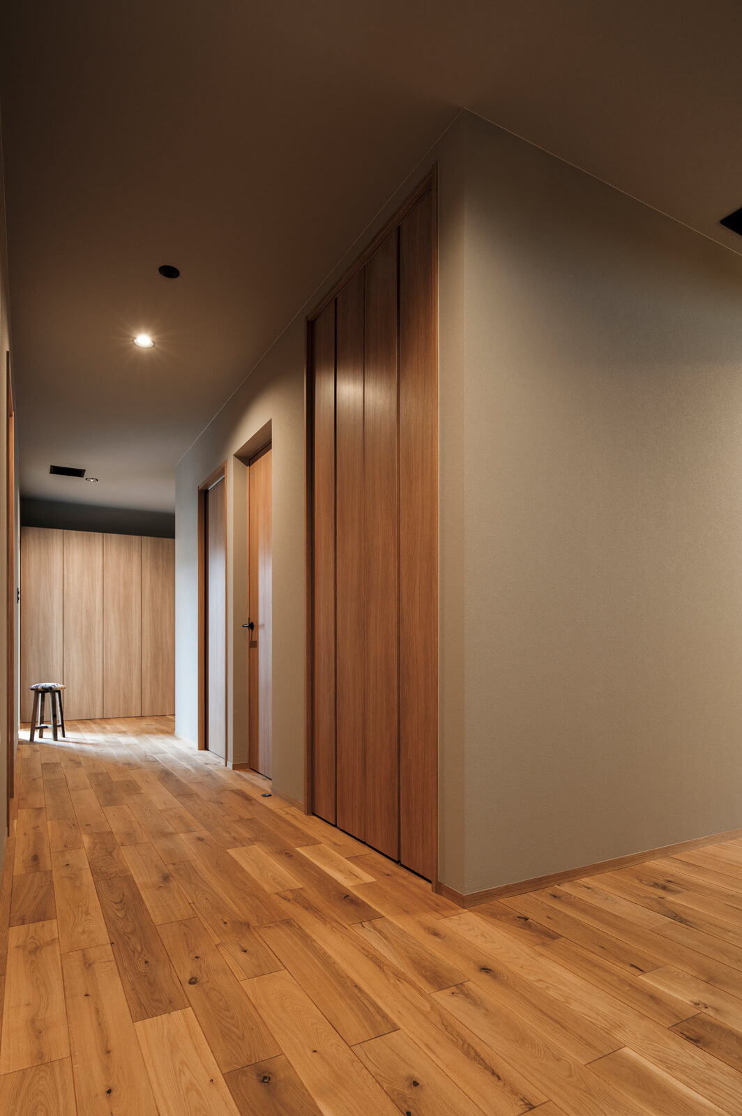 「玄関を開けてすぐにリビングが見えないように」というTさんのこだわりから、奥へと期待感をもたらす廊下を計画。壁をふかしてドアノブを隠し、ラインを美しく整えるなど、細部までこだわり抜いた