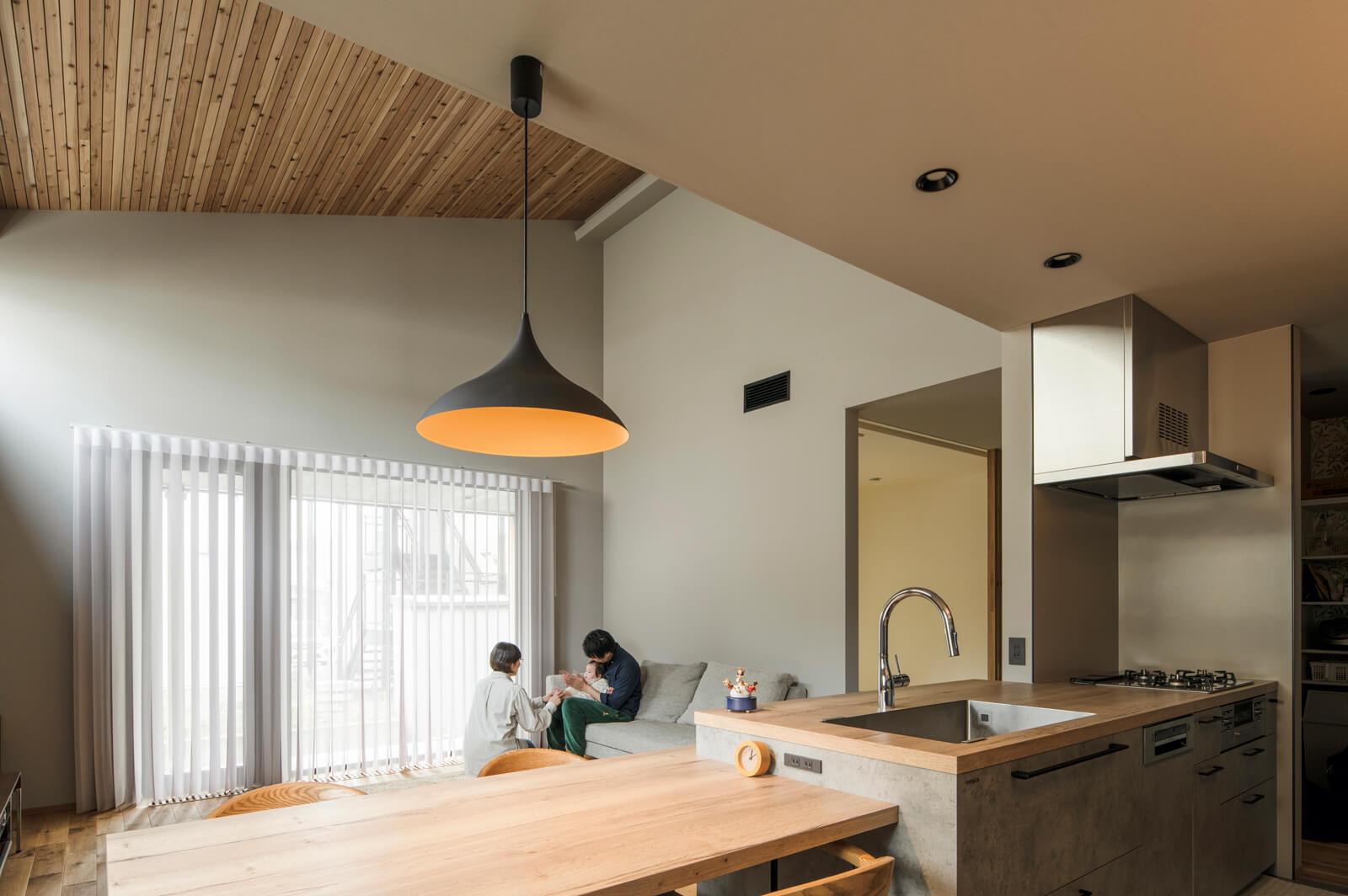 キッチンからリビングを見る。デッキにつながる大きな窓は、庇が日射をコントロールしながら、室内に心地よい光を運んでくれる