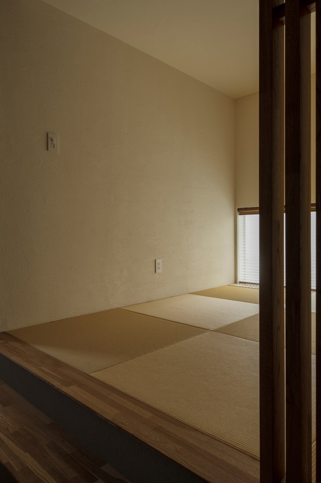 LDKとは視線を切り離した和室。和紙畳は若草色ではなく日焼けしたような色を選び、珪藻土の塗り壁と調和させている。寝転んだり、段差をベンチ代わりにしたりと、多目的に使える居場所となっている