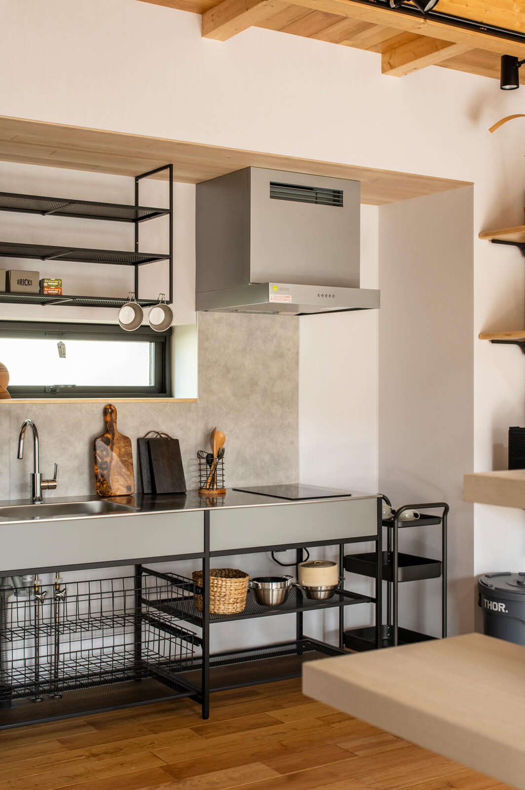 アイアンをアクセントに用いたインテリア性の高い造作の壁付けキッチン。一人暮らしを想定してコンパクトかつ機能的な形で仕上げた