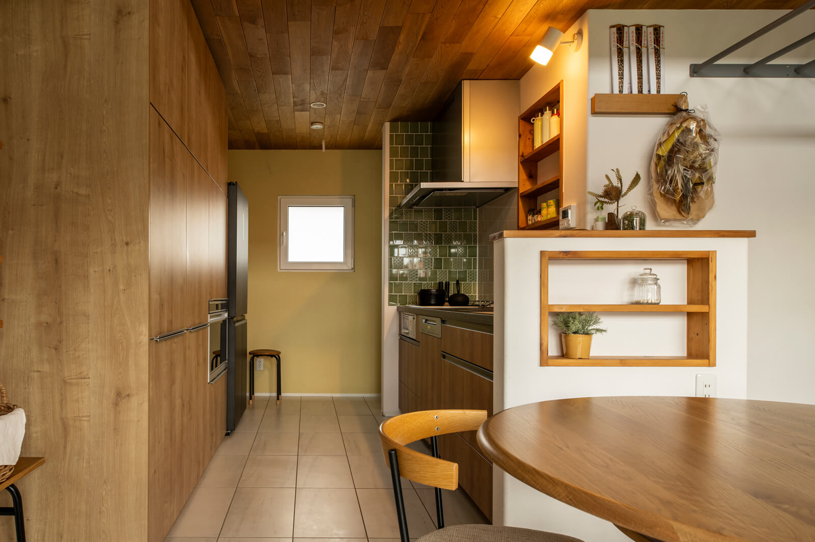 背面に大容量の壁収納やミーレの食洗機を備えた使い勝手の良いキッチン。リビング・ダイニングと自然になじむよう、壁収納は床や天井のナラ材と合うものを厳選した