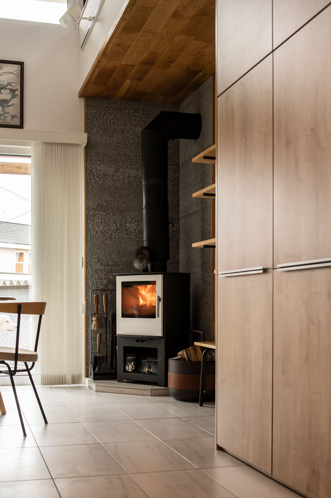 ダイニングの傍らでは、高見さんが「どうしても実現したかった」という薪ストーブの火が揺れる。ストーブはデンマークの「Heta（ヒタ）」社製、床には蓄熱性の高いタイル、炉壁にはSOLIDOを採用した