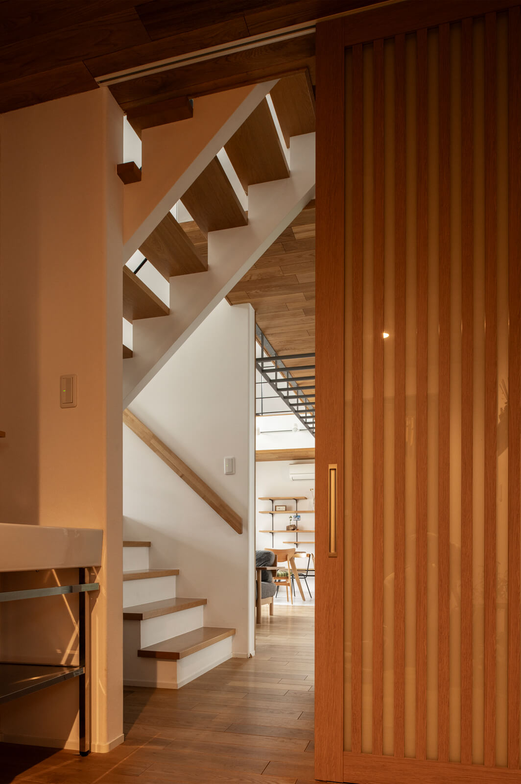 手洗いとトイレを設置した玄関ホールからLDK方向を見る。玄関ホールが暗くならないよう、階段はスケルトン仕様で造作した