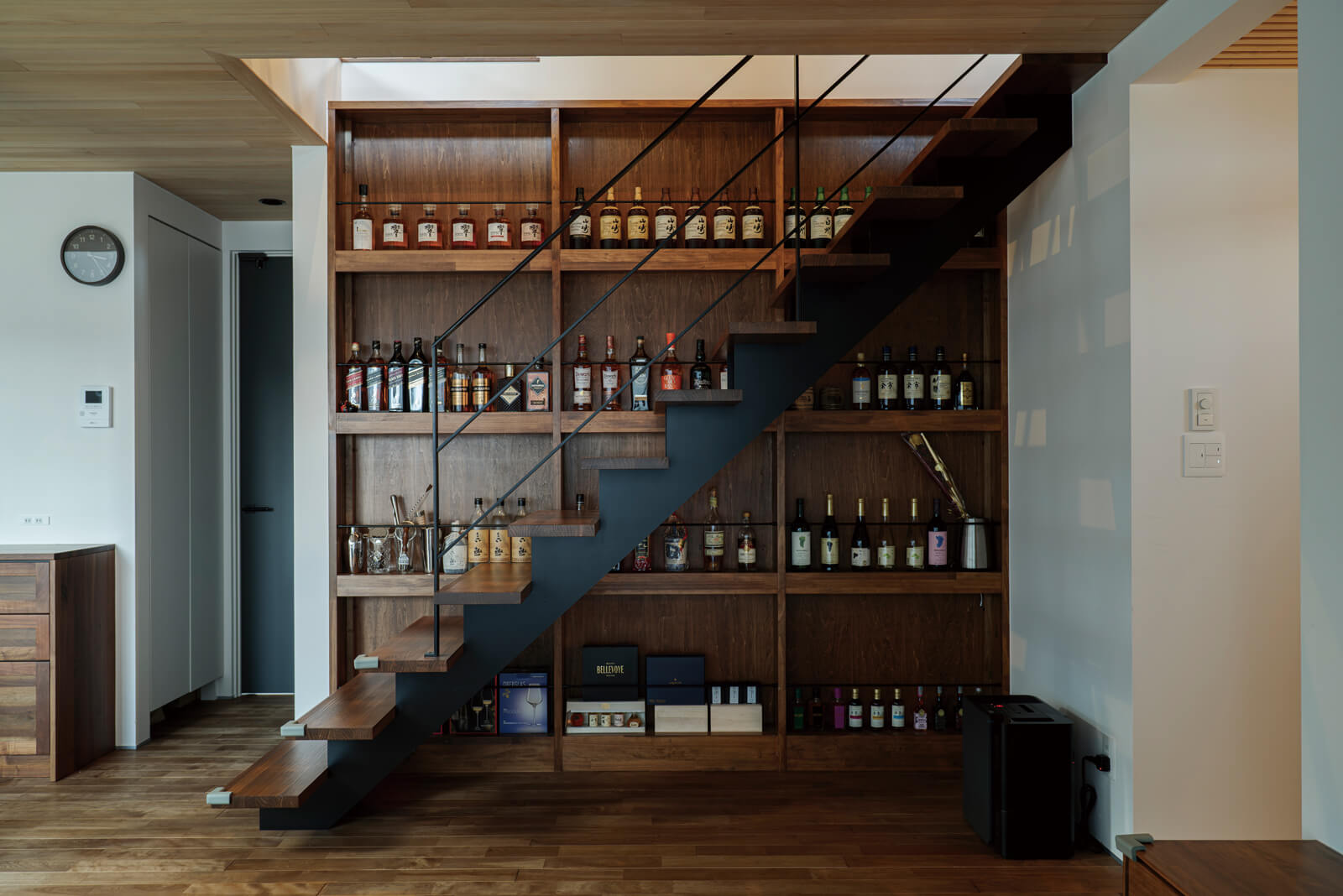 リビング階段の隣にあるのは、Kさんがコレクションしているお酒を飾る棚。棚板の後ろにLEDテープライトを貼っているので、バーのようにライトアップすることもできる