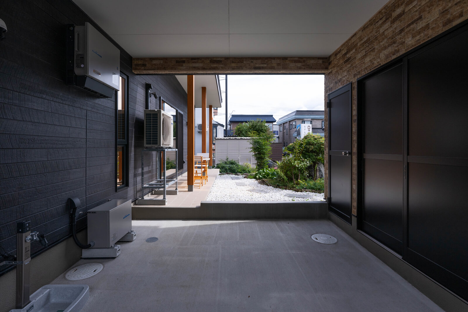 ガレージ内に蓄電池とパワーコントローラーを設置して、雨や雪が直接かからないように配慮した。右側手前は物置、奥はヒートポンプ給湯器エコキュートが収納されている。居住空間から離すことで動作音による騒音を防止する効果がある