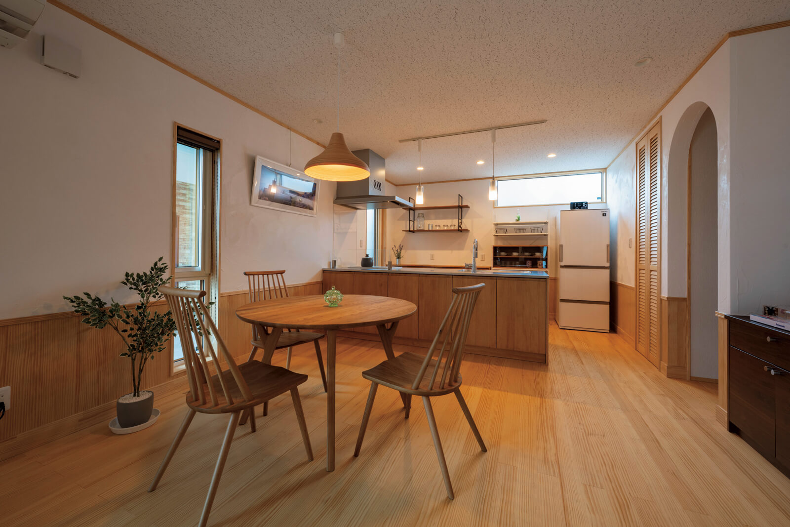 木質感あふれるキッチン。背面には背の高いシステム収納を設置しがちだが、キッチンの高さに合わせた収納にしているため視界が遮られず、空間がより広く見える