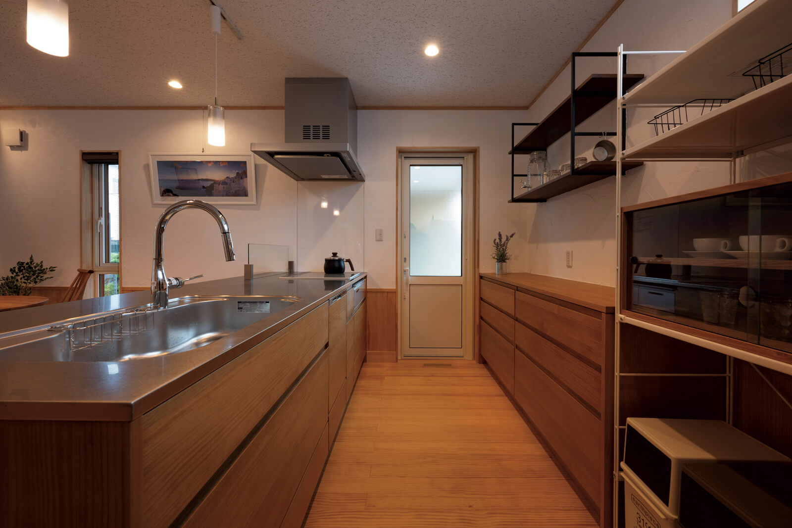 キッチンの天板は、木目にも調和してさびにくいステンレス製。勝手口はガレージにつながっていて、荷物の運び込みに便利