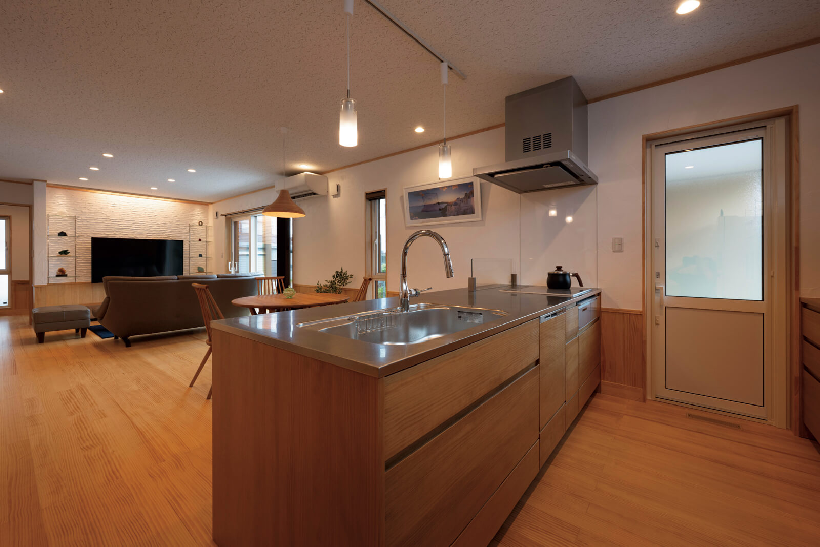 23.5帖の広々としたLDKの床と腰板にはパイン材を採用。もとの間取りでは玄関から狭い廊下が続いていた。廊下をなくし、その分ほかのスペースを広くすることで、限られた面積を無駄なく活用している。高い断熱・気密性能のおかげで、23.5帖のLDKをエアコン1台で十分暖冷房できる