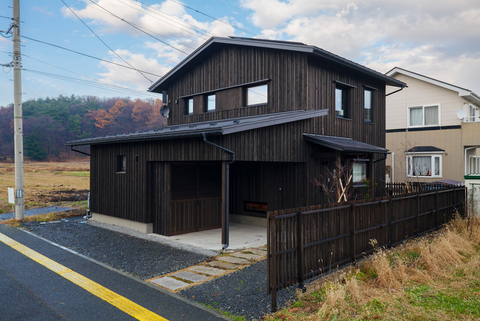 自然の鉱物からつくった保護材「エコ・ウッド・トリートメント」に黒の顔料を混ぜて塗布した県産スギ材の外壁。一度塗布すると60年以上メンテナンスの必要がない。オープンテラスに設置された物置の中に、外水道や室外機が隠されている