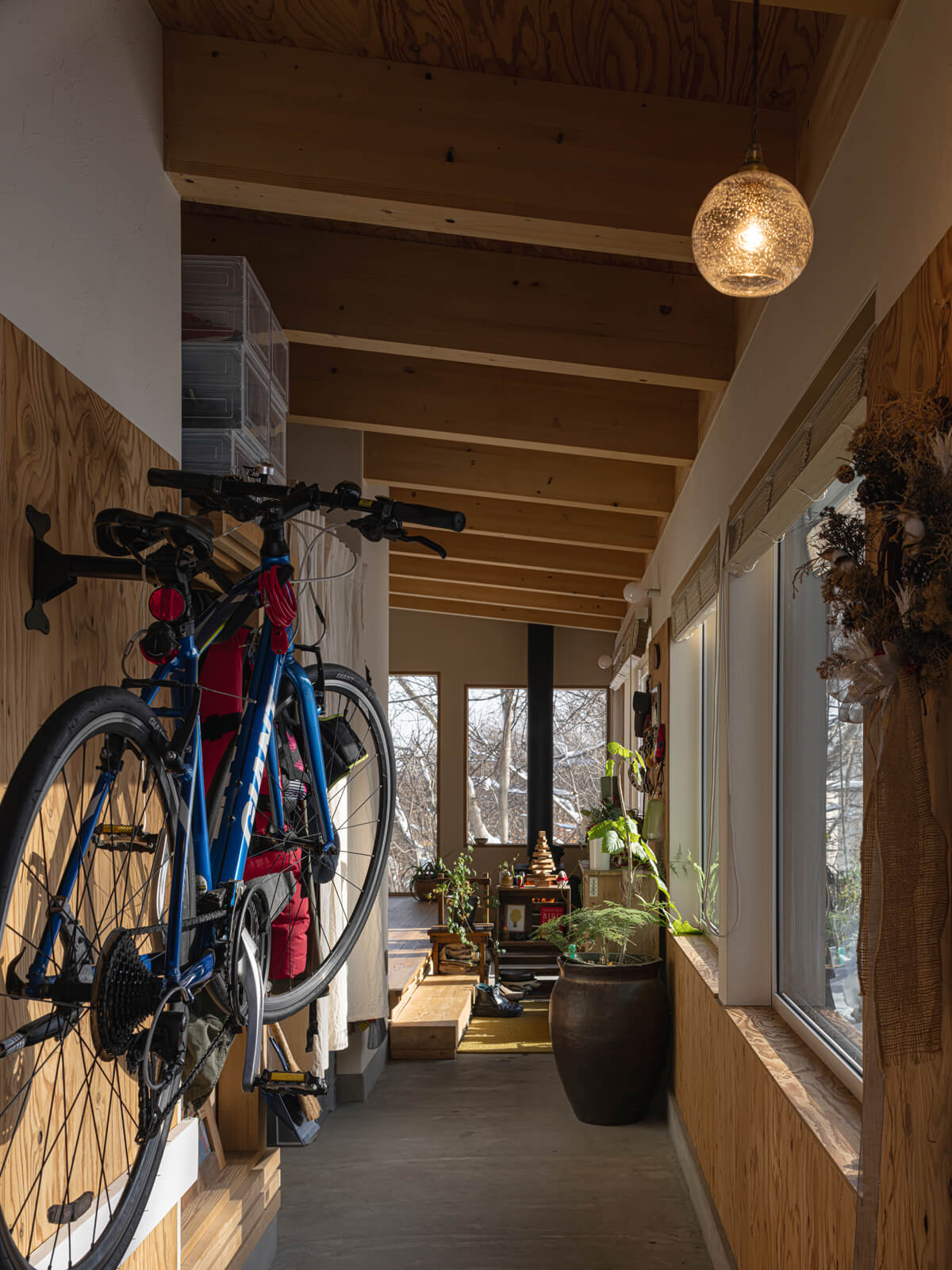 ドアを開けると、南面の窓辺に沿って通り土間がまっすぐに伸びる。正面の窓の向こうが雑木林で、視線が抜けて広さが感じられる