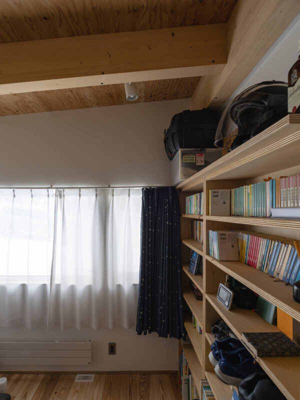 水まわりと隣接する個室の一つは、「本棚をたくさん設けた個室がほしい」という要望を叶えたKさんの寝室。壁一面の本棚も、シナベニアを用いた造作の本棚にも大工の技が光る