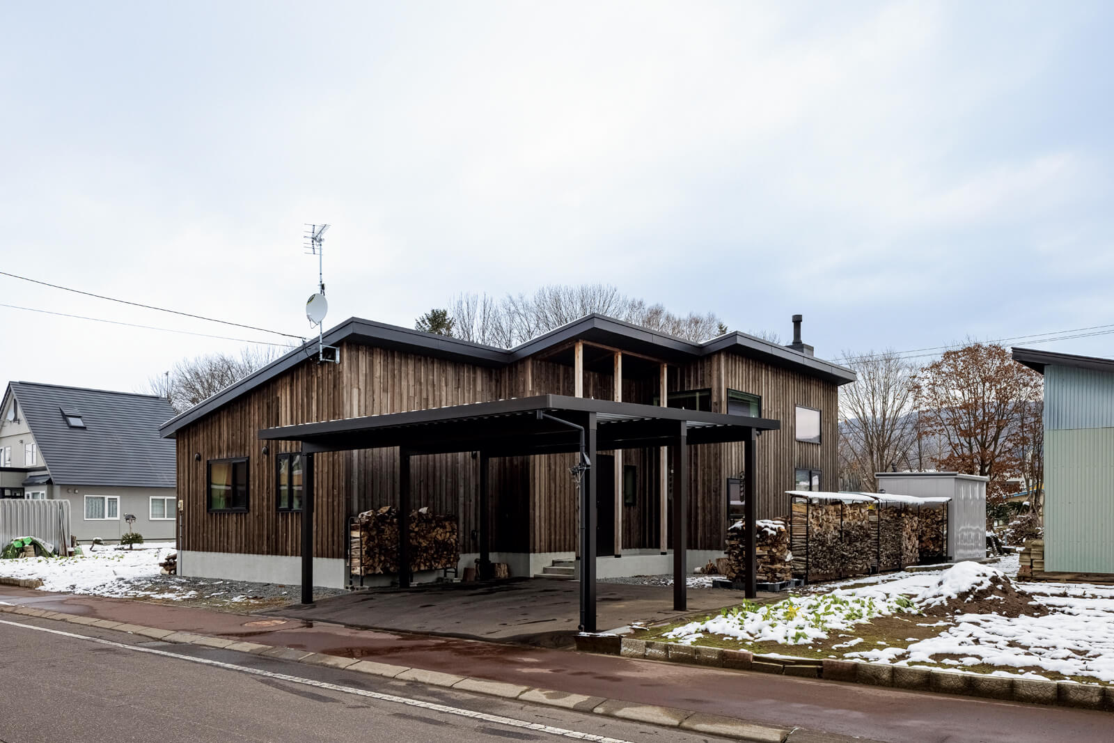 大工の手仕事で仕上げられたカラマツ板張りの外壁が端正な佇まいをつくる外観。屋根付きカーポートで雪対策も万全