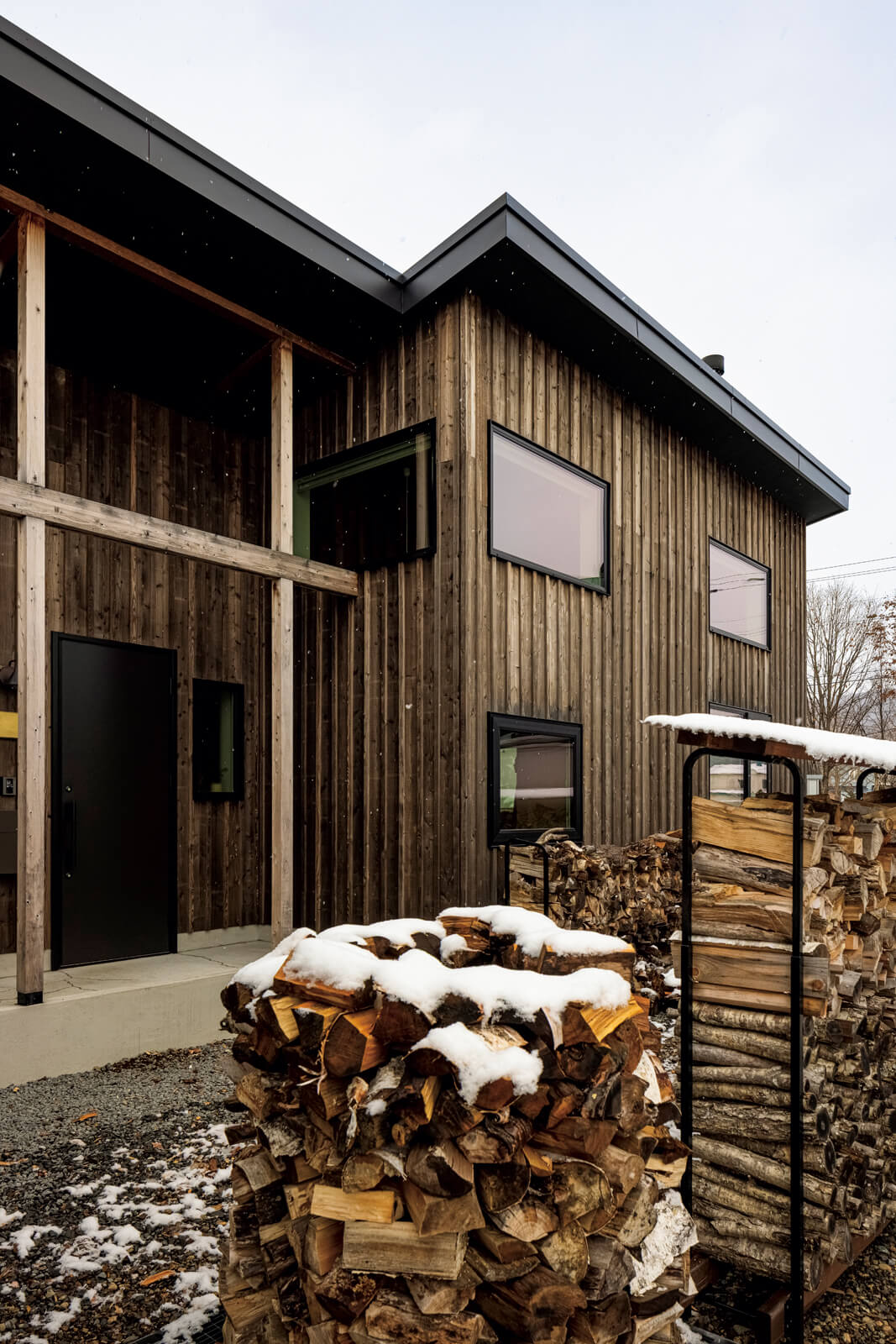 Sさんの手で丁寧に積まれた薪が「木の家」の外観としっくりとなじむ