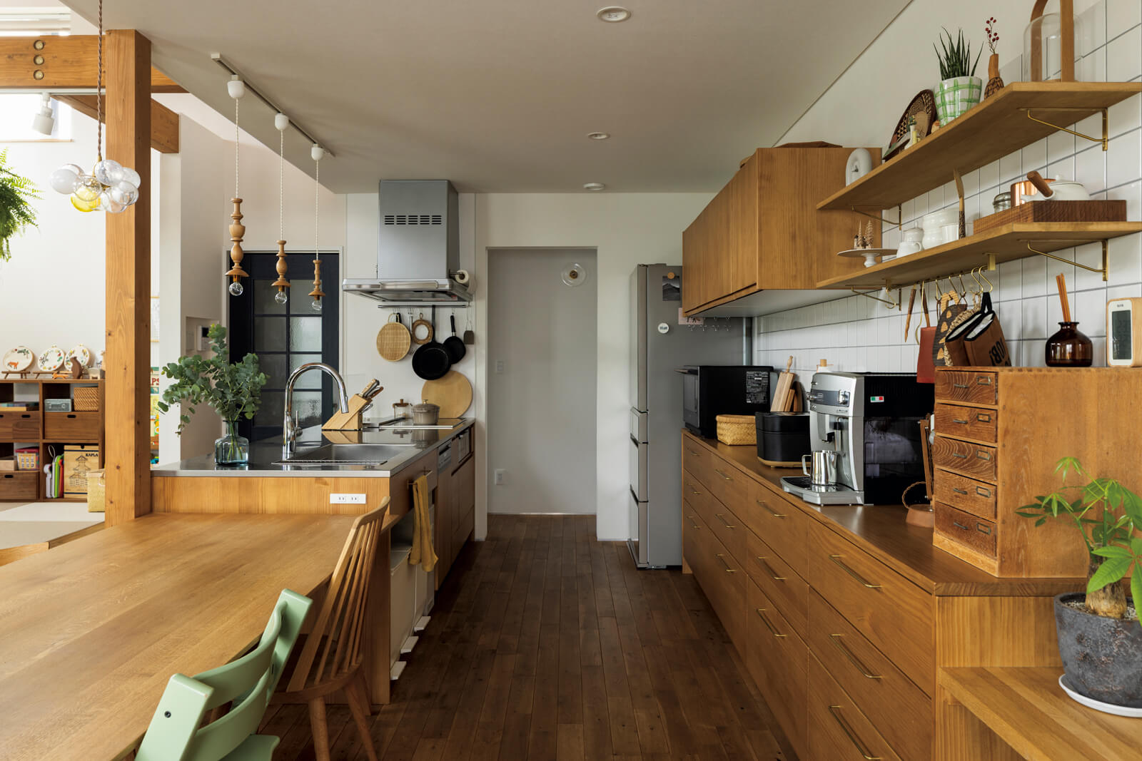 ウッドワンのシステムに施主支給の真鍮製ハンドルを組み合わせ、コストコントロールしながら造作風に仕上げたキッチン。通路幅も広く取り作業性の向上も図った