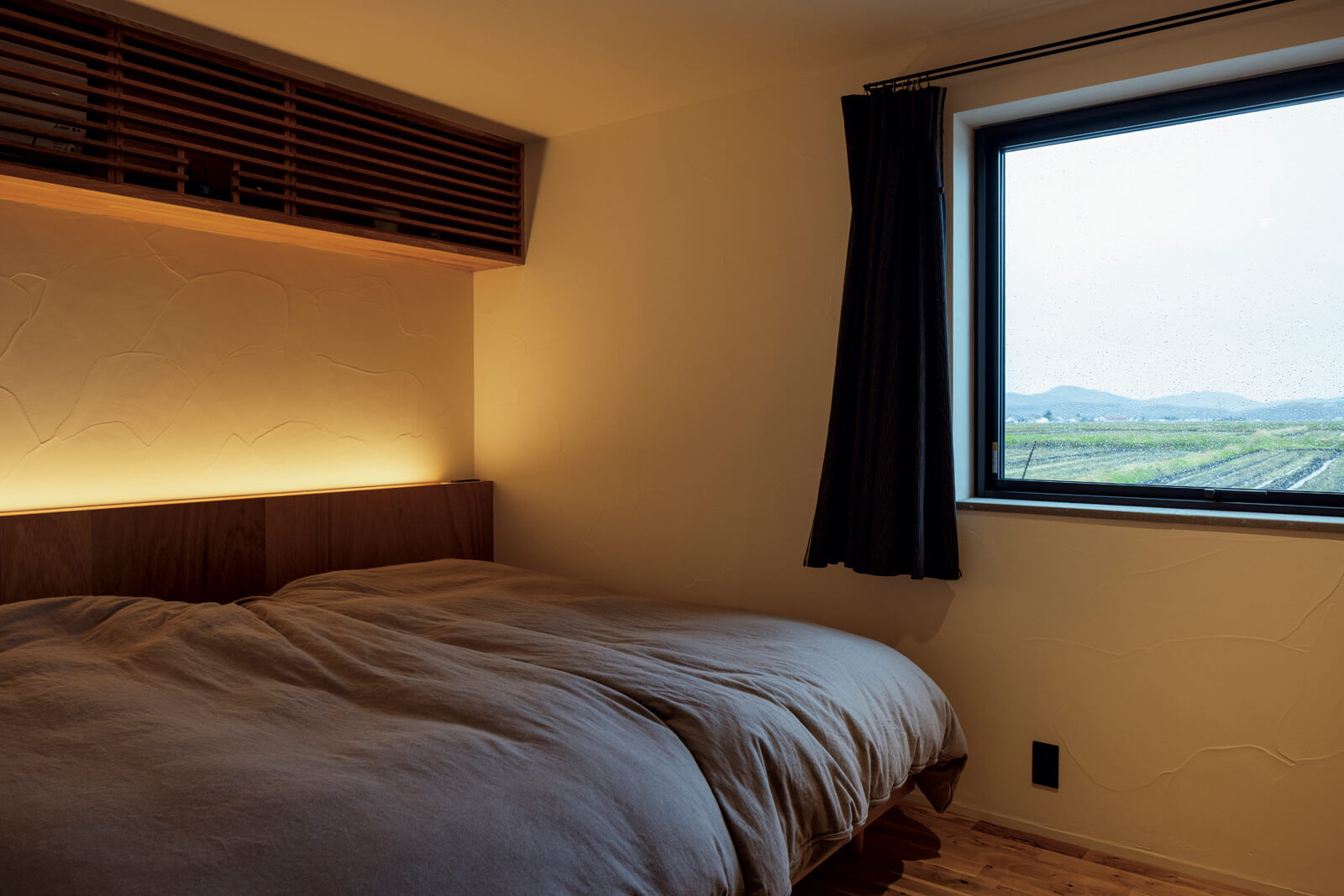 1階の水まわりに隣接して寝室をレイアウト。大きく取った開口に映る四季折々の田園風景は一枚の絵画のよう