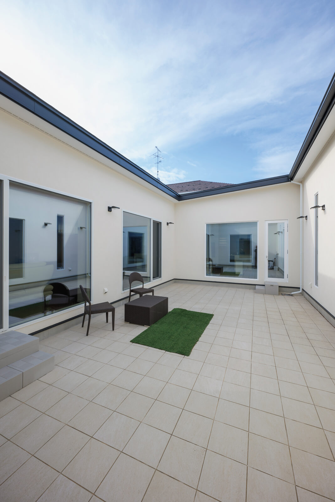 約30帖の広々とした中庭。塗り壁、床のタイルもベージュで統一感を演出した。二世帯ともLDKの大きな窓は中庭に面しているので、往来するためのアプローチとしての役割も持つ