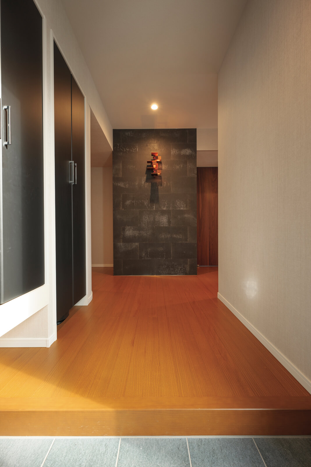 玄関ホール正面の化粧壁は瓦と同じ素材でつくられた壁材。そこに配された壁面照明はフランク・ロイド・ライトがデザインした「TALIESIN 3 WALL SCONCE」