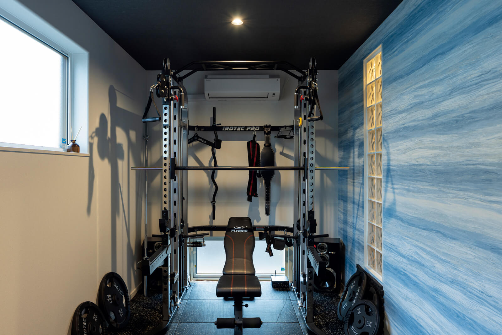 Wさんの要望で、リビングに隣接して本格的なトレーニングルームを設置。ガラスブロックを用いた間仕切り壁は、Wさんと森下さんがDIYで仕上げた。「コーキングのデコボコさえも愛おしく感じます」