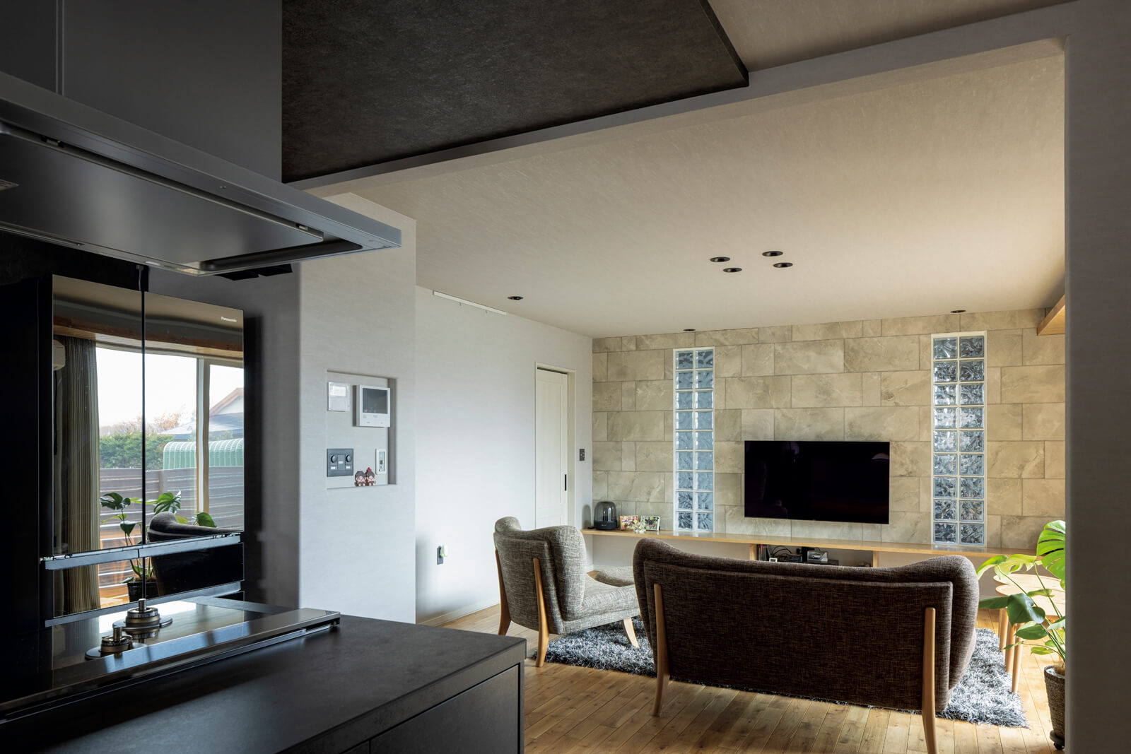 エコカラットとガラスブロックを採用した壁をアクセントにしたリビング。壁の裏手はWさんのトレーニングルーム。ゆったりとしたリビングは、親子の生活空間を緩やかに分離する役割も