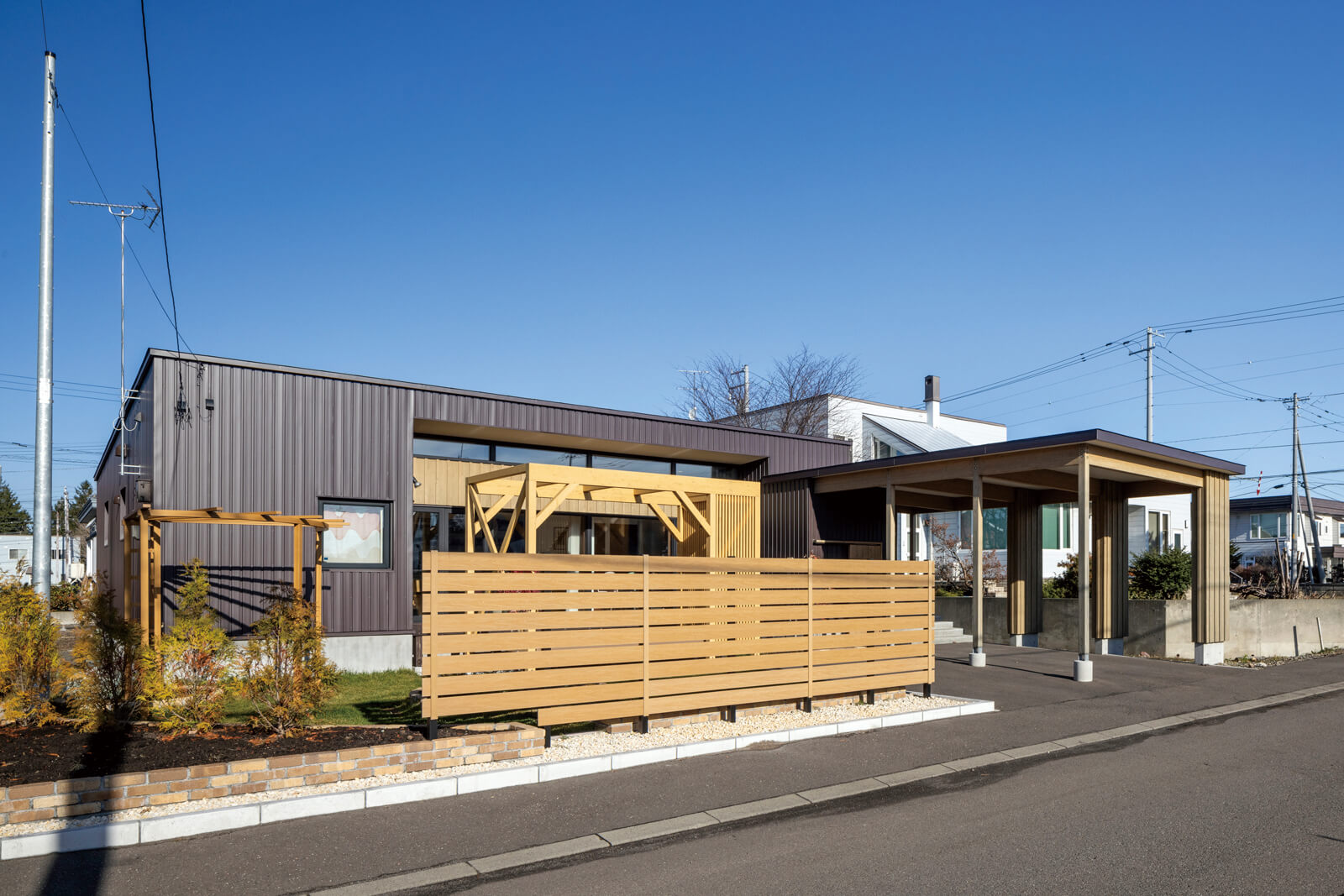 外構、庭の造作と一体となったOさん宅の外観。フラットに仕上げた住まいは基礎を高く設え、万が一の水害への備えも万全