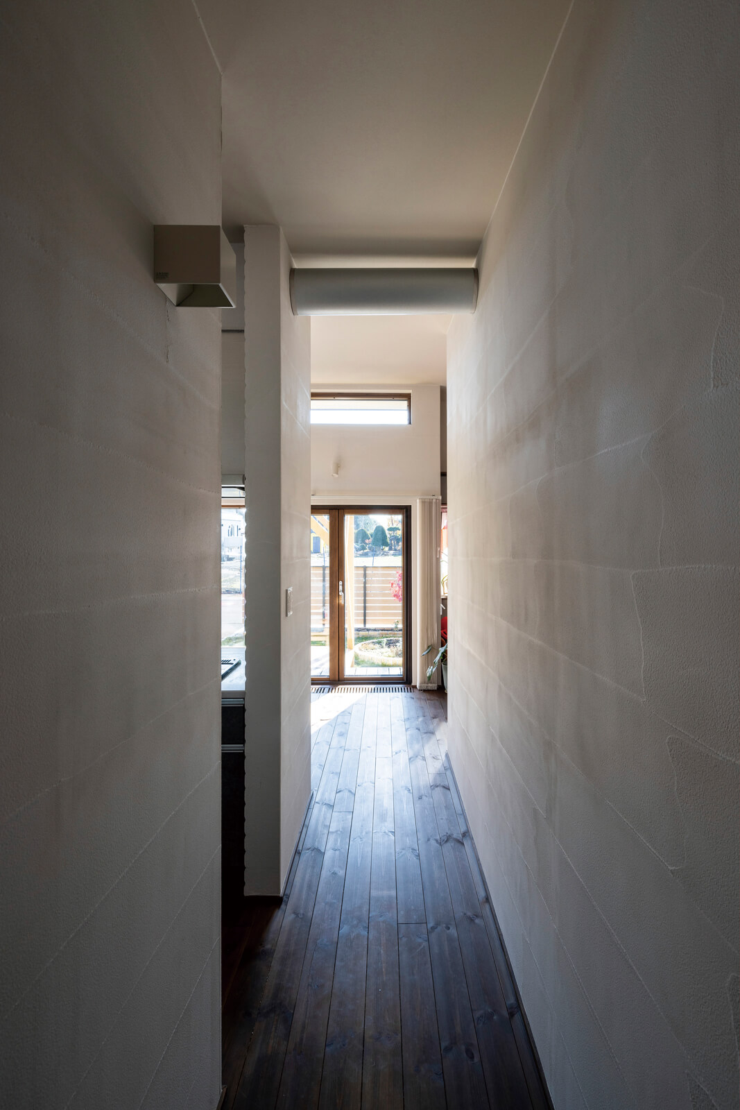 しっくい塗り壁の質感が心地よい室内。キッチン脇に設けた通路は、寝室や水まわりを集約したプライベート空間へつながる