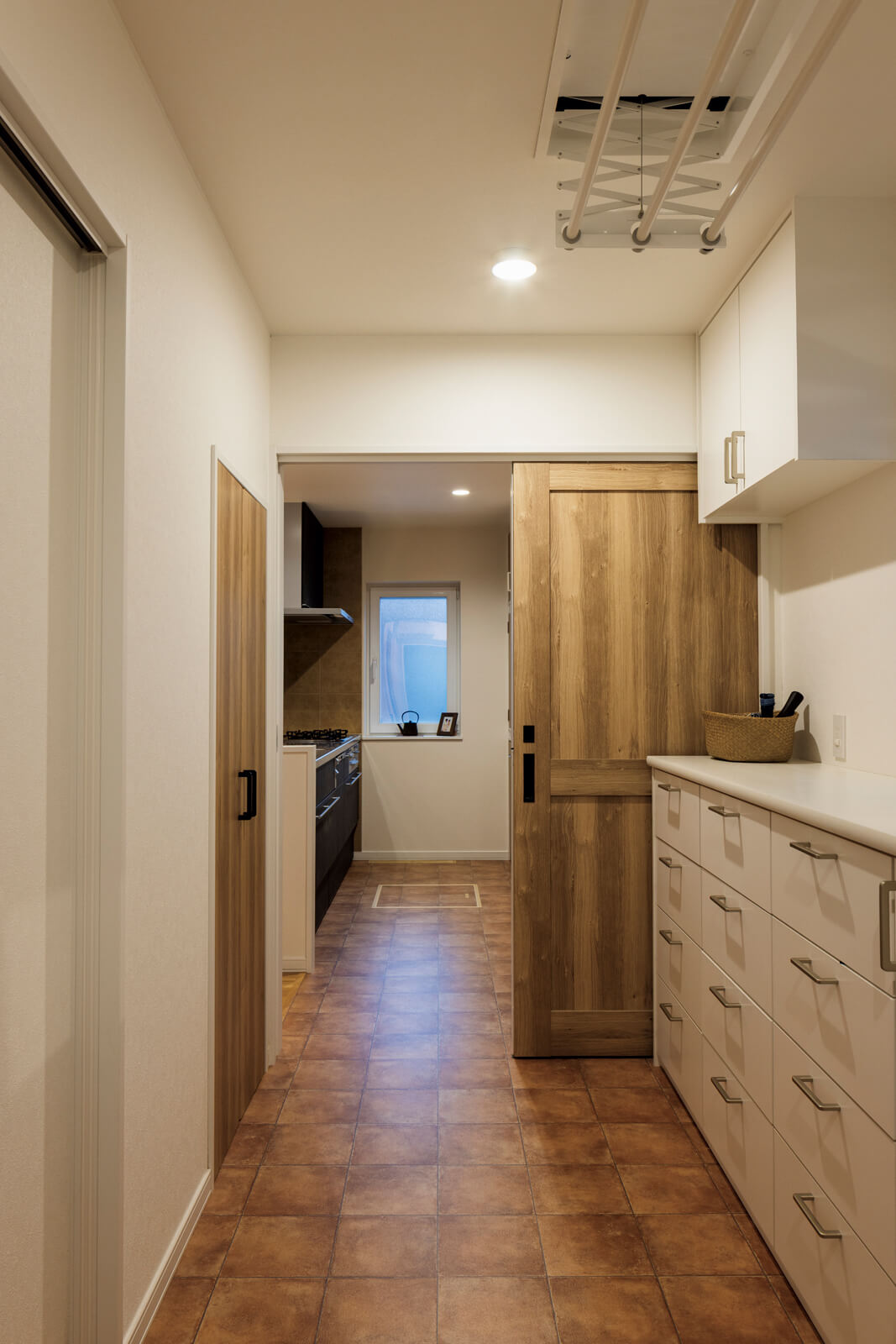 キッチンに隣接して、洗濯家事が1ヵ所で完結できる洗濯・脱衣室をレイアウト。造作収納を充実させ、アイロンがけや衣類を畳むのにちょうどいい長さのカウンターも設えた