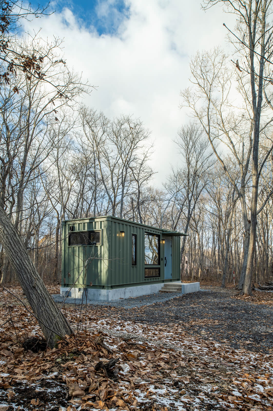 駒ヶ岳山麓の森の景色に溶け込むようなオリーブグリーンのコンテナハウス。下水処理設備の埋設、LPガスボンベ庫の設置など、暮らすためのインフラも整えられている